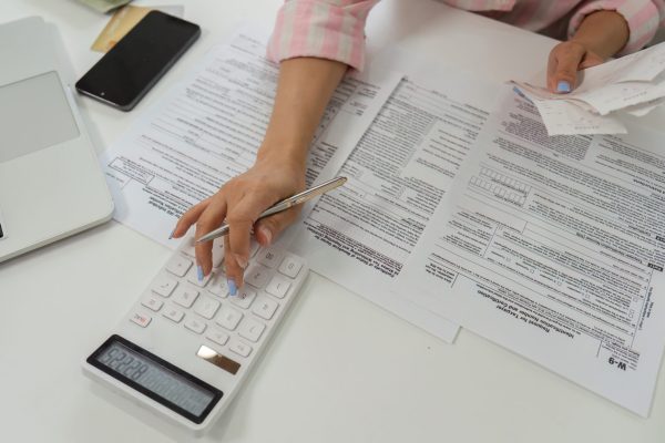 In her home office, a woman checks papers and uses a pen to ensure her financial records are in order for tax preparation.