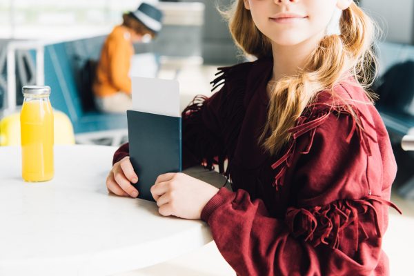 partial view of preteen kid with passport and air ticket in airport